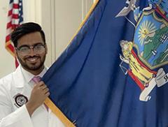 Asim Ali holding his home home state flag - NY 