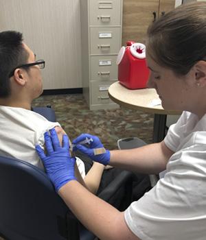 Man recieving injection from pharmacist