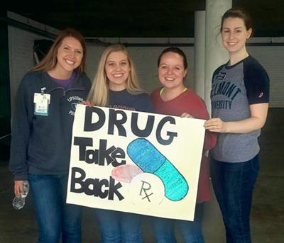 Holding 'Drug Take Back' sign