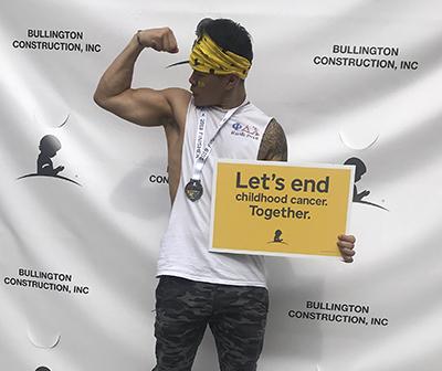 Nam Le flexes muscles during child cancer awareness event. 